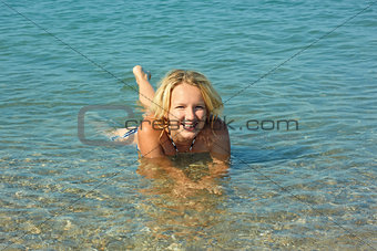Teenage girl lying in coastal seawater