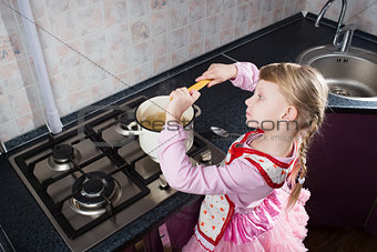 little girl putting pasta in the pot 