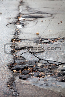 Broken pavement and pothole asphalt road after winter.