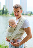 Father carrying his son in sling outdoors