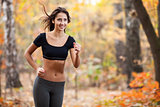 Happy young woman running in autumn fores