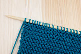 Garter stitch in teal yarn on knitting needle