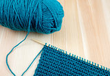 Ball of blue wool with knitting on the needle