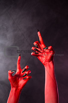 Creepy red devil hands with black nails  