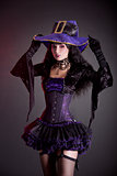Smiling witch in purple and black gothic Halloween costume  