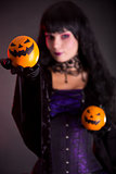 Pretty witch holding Jack o lantern oranges 