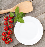 Empty plate on wooden with tomatoes and utensil