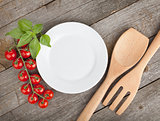 Empty plate on wooden with tomatoes and utensil