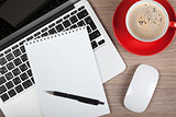 Blank notepad over laptop and coffee cup