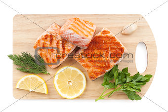 Grilled salmon with lemon slices and parsley on cutting board