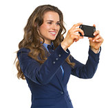 Smiling business woman taking photo using cell phone