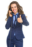 Happy business woman talking phone and showing thumbs up