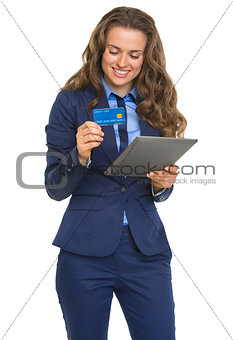Smiling business woman with credit card using tablet pc