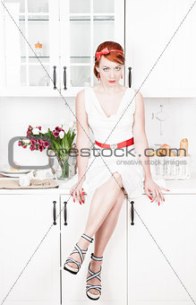 Beautiful woman sitting on the kitchen table