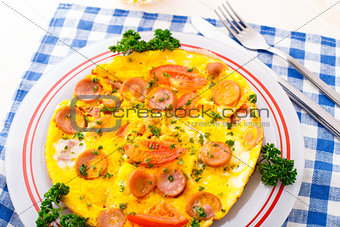 Omelette with slices of sausage and tomato