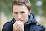 Young man warming hands with breathe