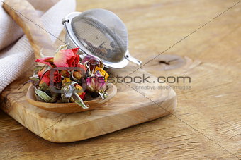 herbal tea from the dried flower buds of roses in a wooden spoon