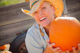 Beautiful Blond Female Rancher Wearing Cowboy Hat Holds a Pumpki
