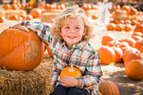 Little Boy Sitting and Holding His Pumpkin at Pumpkin Patch 