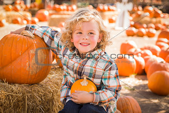 Little Boy Sitting and Holding His Pumpkin at Pumpkin Patch 