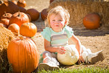 Adorable Baby Girl Holding a Pumpkin at the Pumpkin Patch 