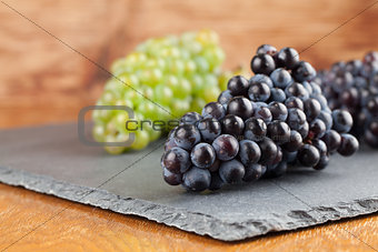 Blue and green grape clusters on slate board