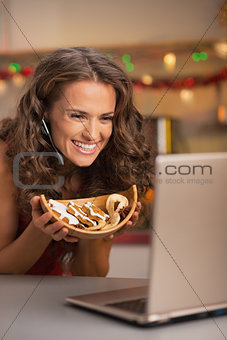 Happy young woman showing christmas cookies while having video c