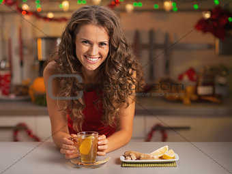 Smiling young woman drinking ginger tea in christmas decorated k