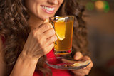 Closeup on happy young woman drinking ginger tea with lemon