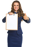 Happy business woman showing blank clipboard and thumbs up
