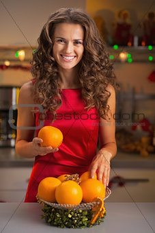 Happy young housewife decorating christmas plate with oranges