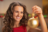 Happy young woman in red dress holding christmas ball
