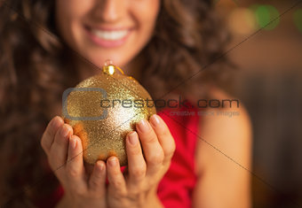 Closeup on christmas ball in hand of smiling woman in red dress