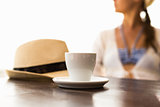 Cup of coffee, hat and woman at the background