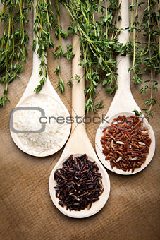 Red and white rice on wooden spoons