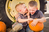 Two Boys Sitting Against Tractor Tire Holding Pumpkins Whisperin