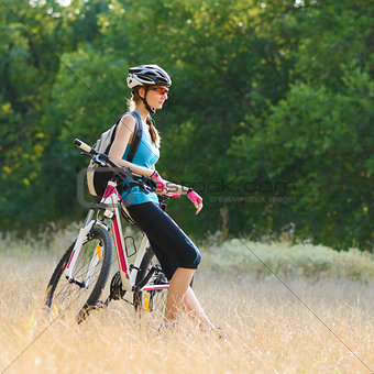 Young Attractive Woman Resting with Bike in the Beautiful Forest