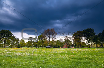 house on flowering meadow during storm