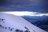 Off-piste slope and cloudy sky at sunset