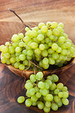 Bunch of green grapes in bowl on wooden table