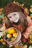Little girl with autumn pumpkins in a basket 