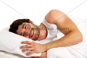 Man laid in white bed smiling