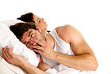 Tired man laid in white bed next to a sleeping woman