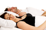 Woman laid in white bed next to a man sleeping 