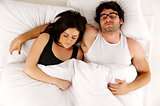 Man and woman laid in white bed asleep cuddling
