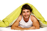 Man smiling in bed under a green duvet