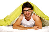 Man smiling in bed under a green duvet