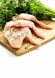 Raw chicken wings on chopping board with herbs