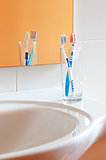 Colorful toothbrushes in a glass in bathroom