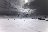 Ski slope, skiers and sky with storm clouds